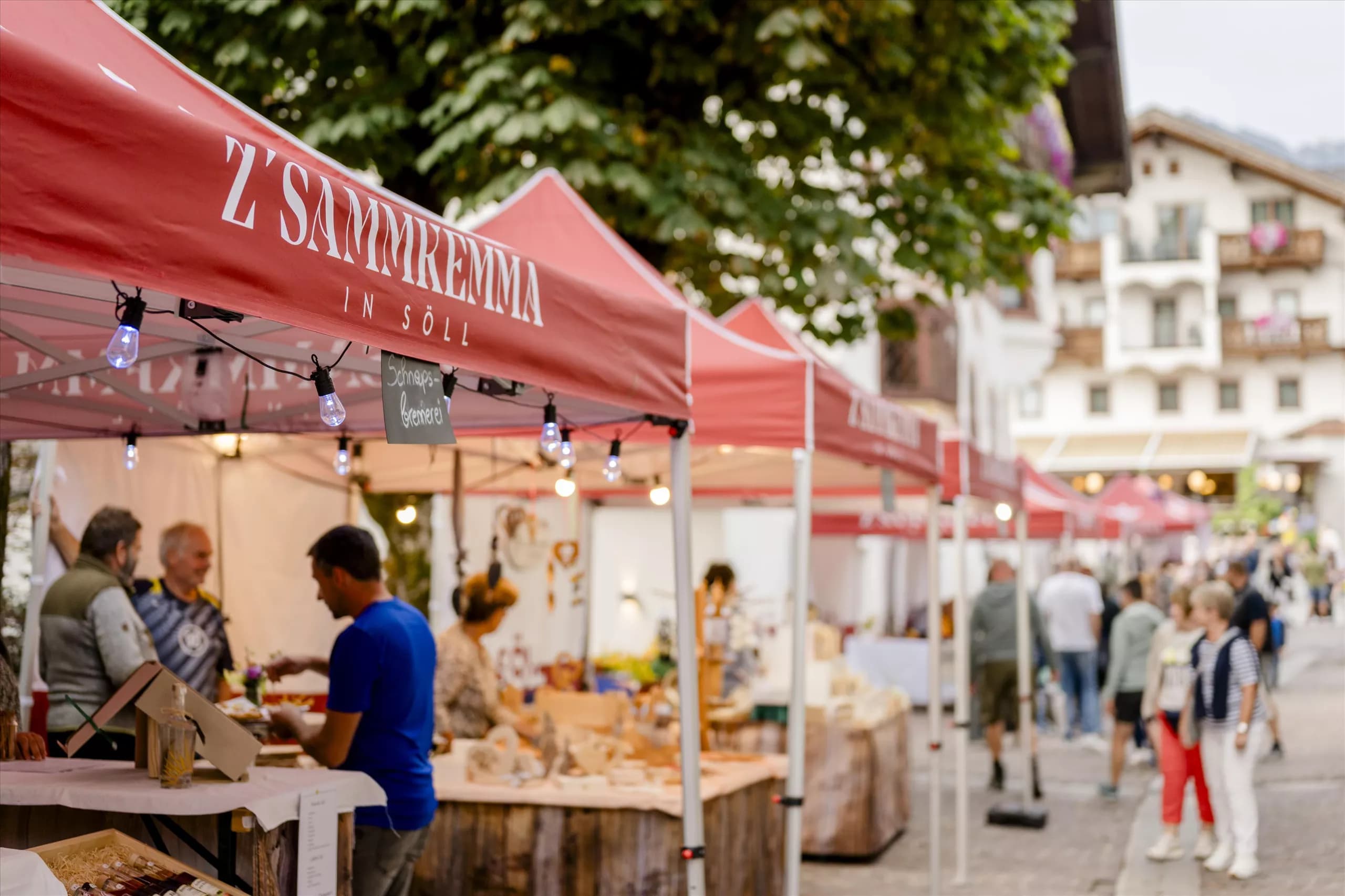 A lively marketplace at twilight with stalls offering local products. People stroll through the alleys and enjoy the atmosphere.